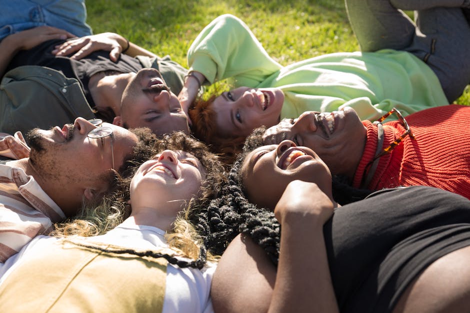 A group of diverse people smiling and relaxing on yoga mats outdoors.